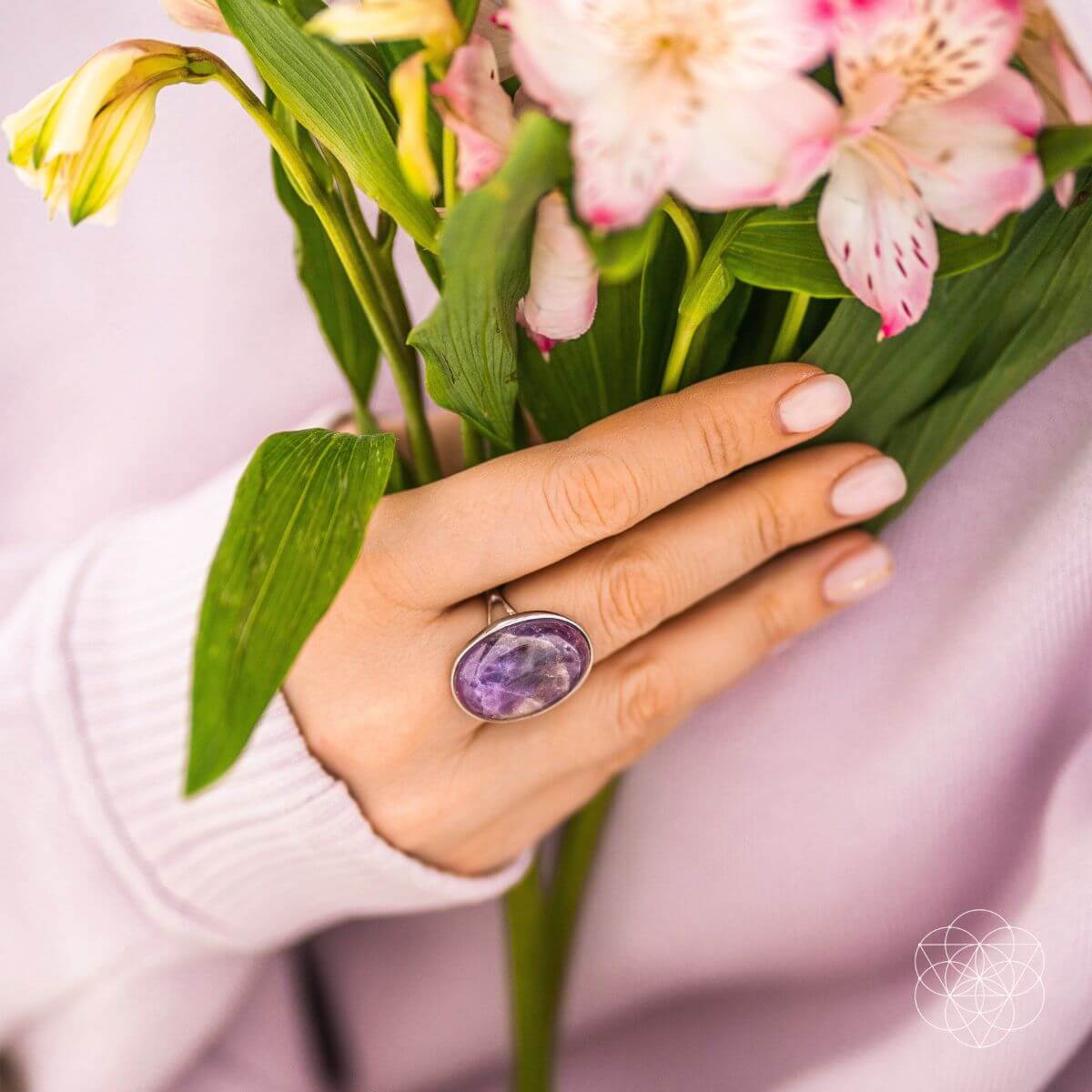 Hand wearing a purple gemstone ring holding a bouquet of flowers