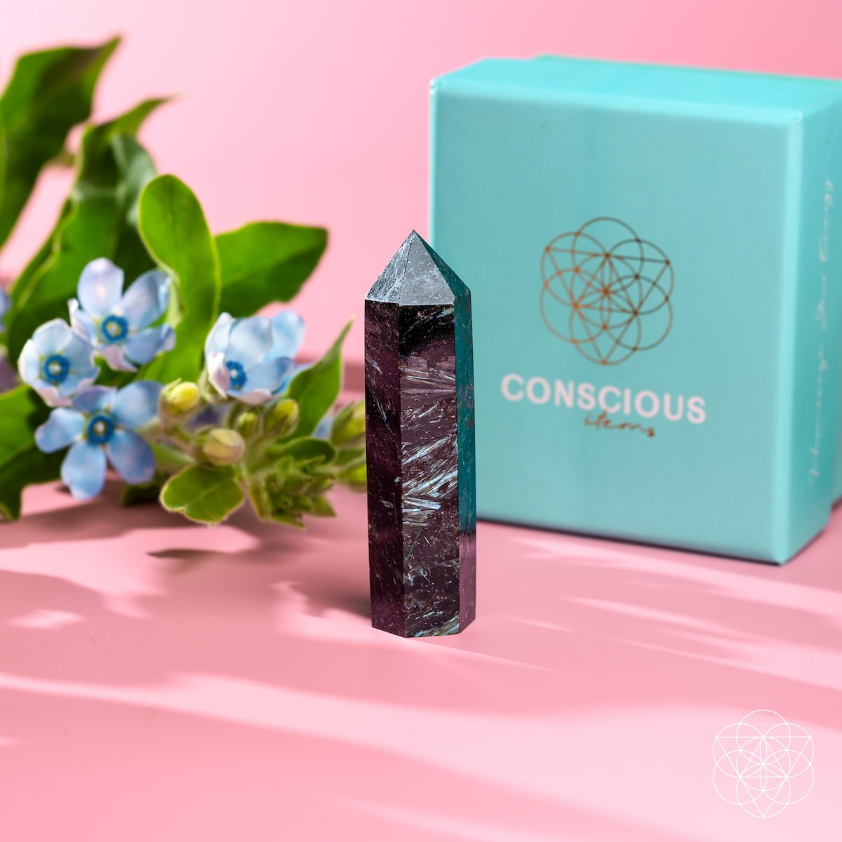 Crystal tower with 'Conscious' box and flowers on a pink background