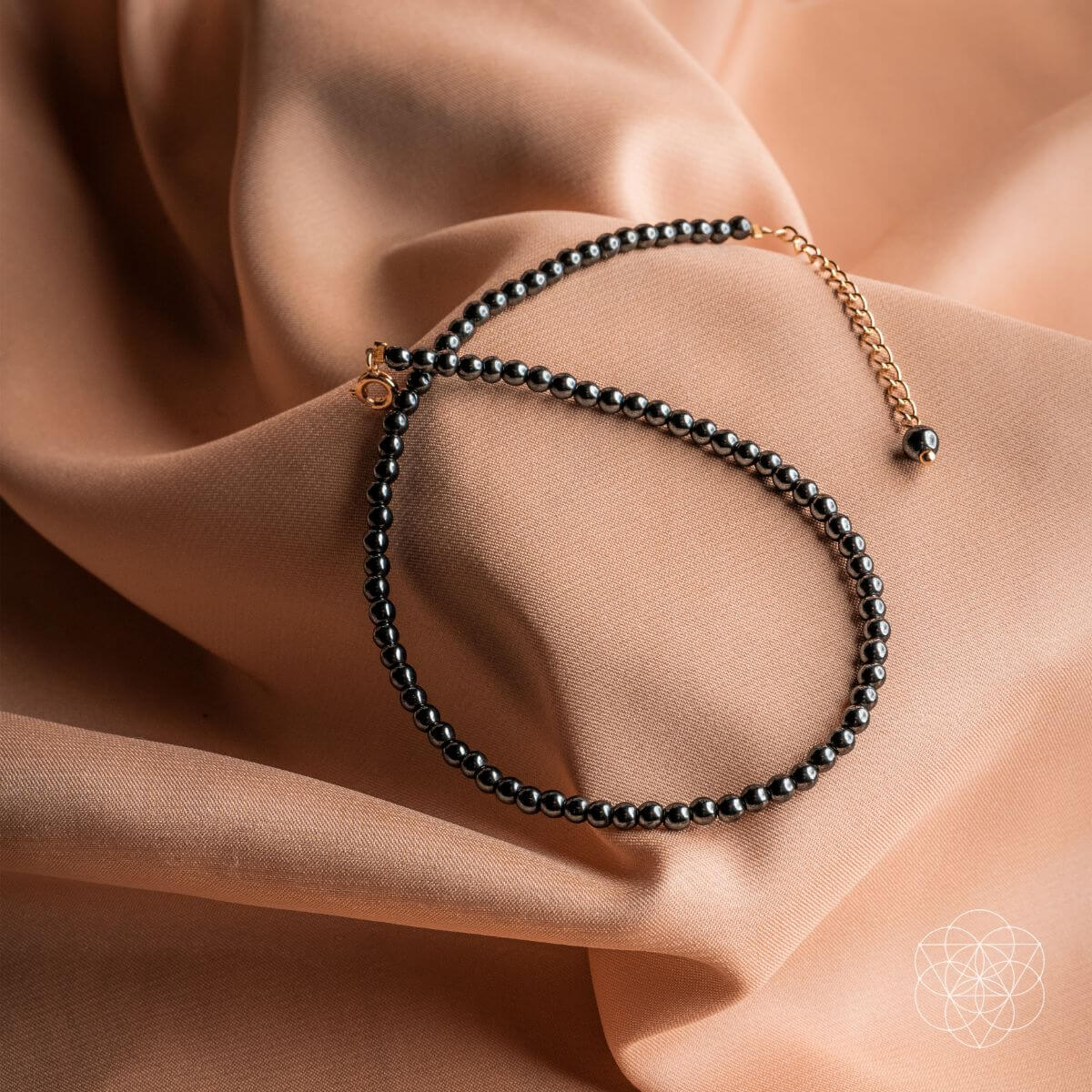 Black beaded bracelet on a beige fabric background