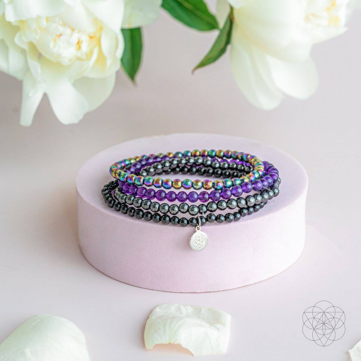 Stack of beaded bracelets on a pink stand with flowers in the background