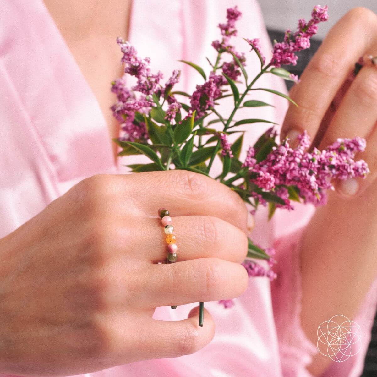 Person holding a small bouquet of pink flowers with a pink background
