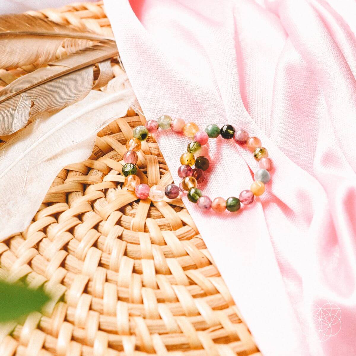 Multicolored beaded bracelet on a woven surface with pink fabric