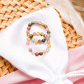Multicolored beaded bracelet on a white cloth with a woven background