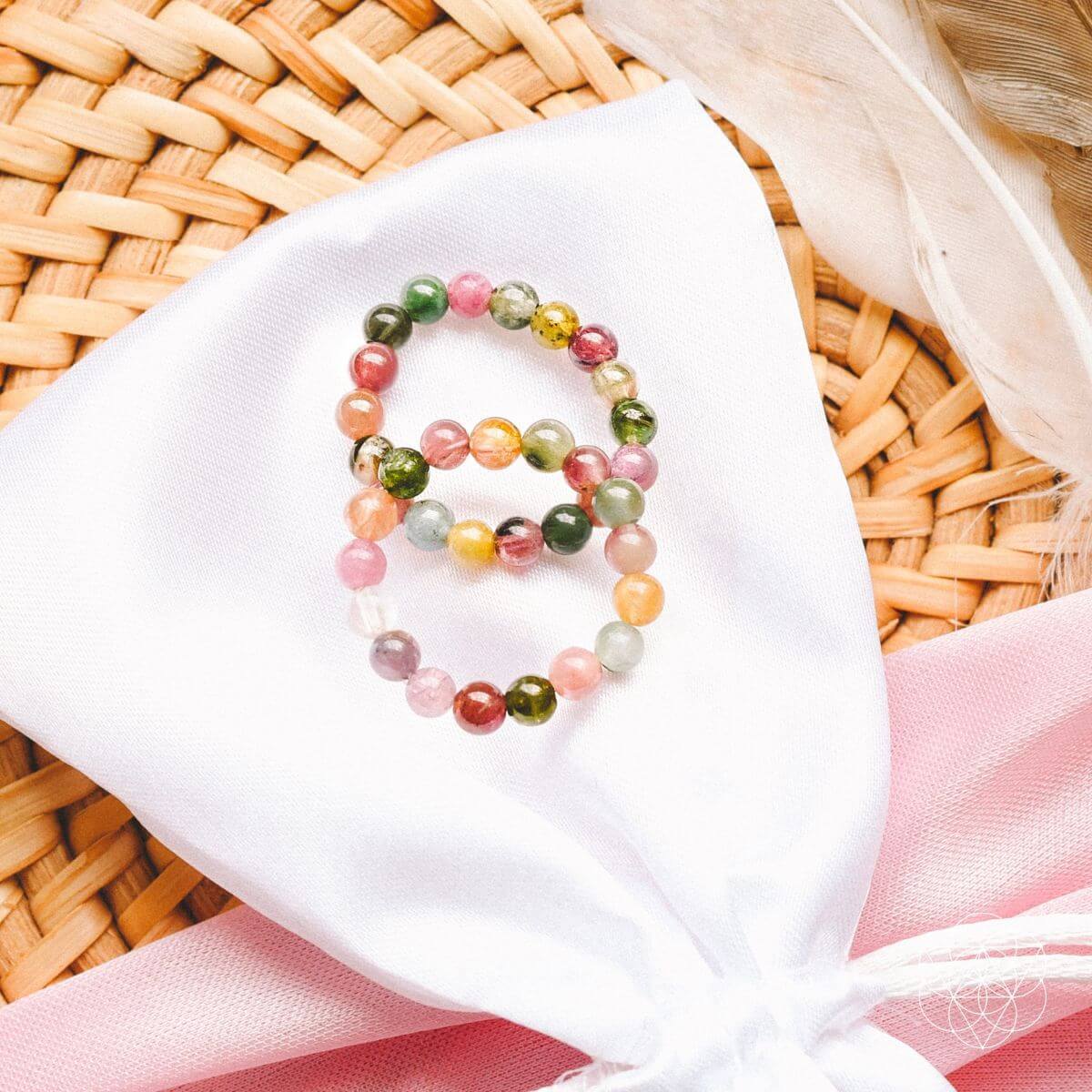 Multicolored beaded bracelet on a white cloth with a woven background
